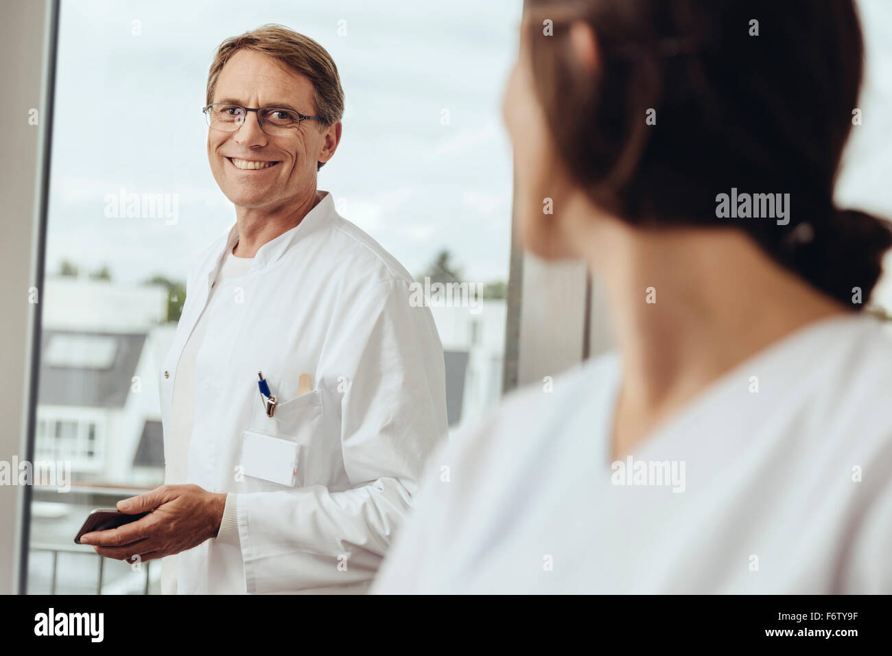 Doctor and nurse talking in hospital room, smiling Stock Photo - Alamy