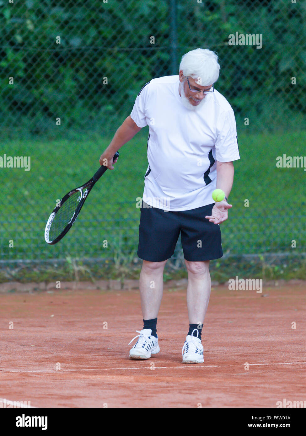 Senior man playing tennis on a gravel court Stock Photo Alamy