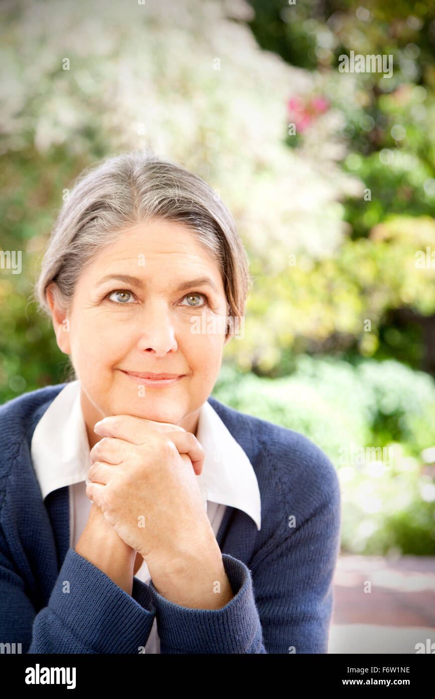 Portrait of smiling matur woman sitting in the garden Stock Photo