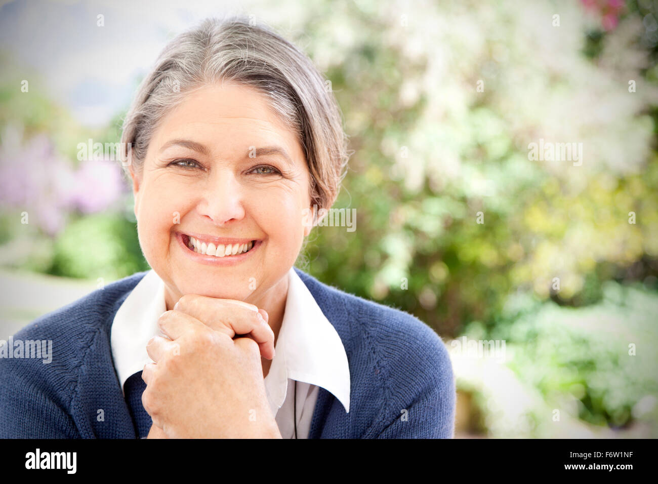 Portrait of smiling matur woman sitting in the garden Stock Photo