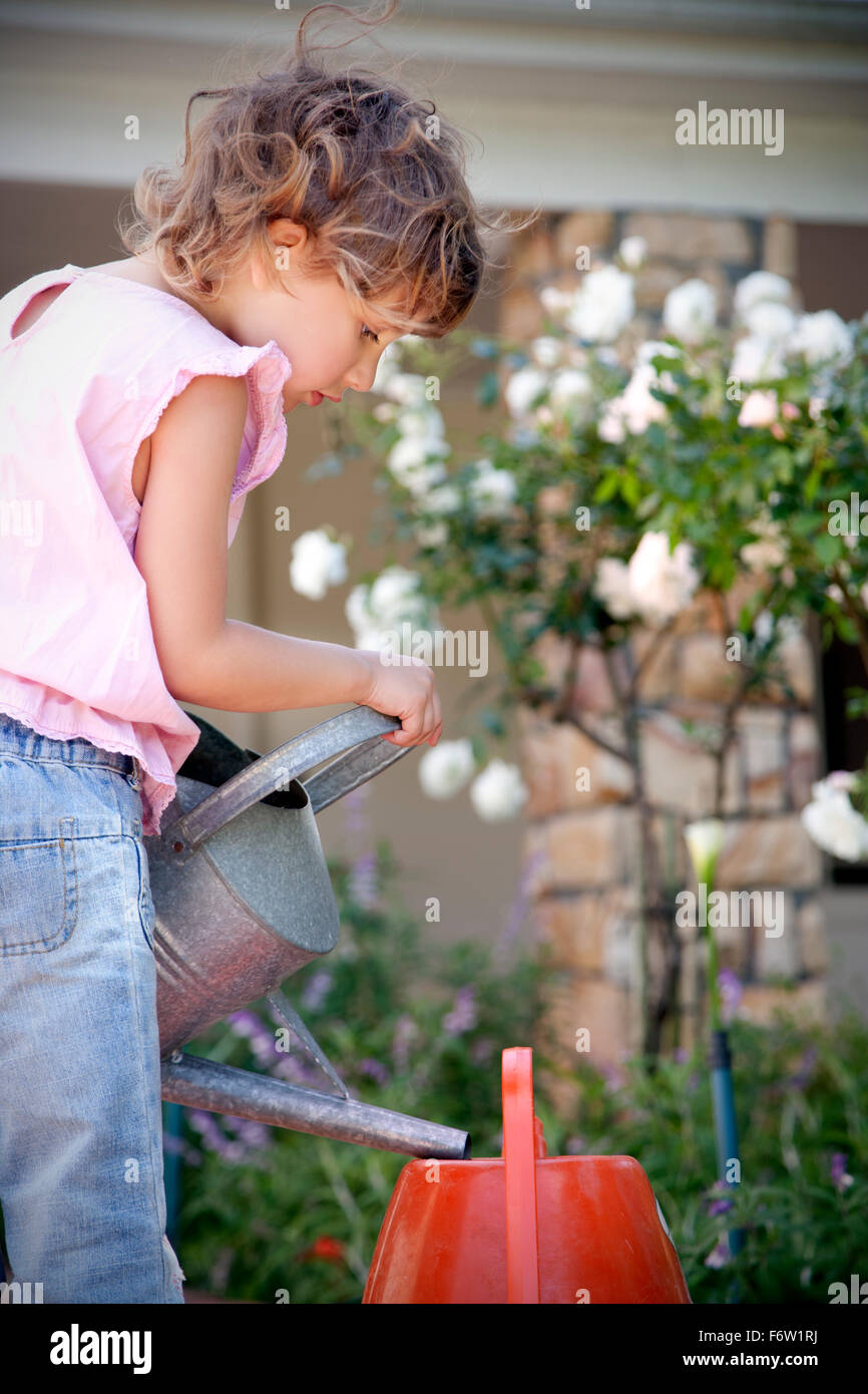 Little girl with watering can in the garden Stock Photo