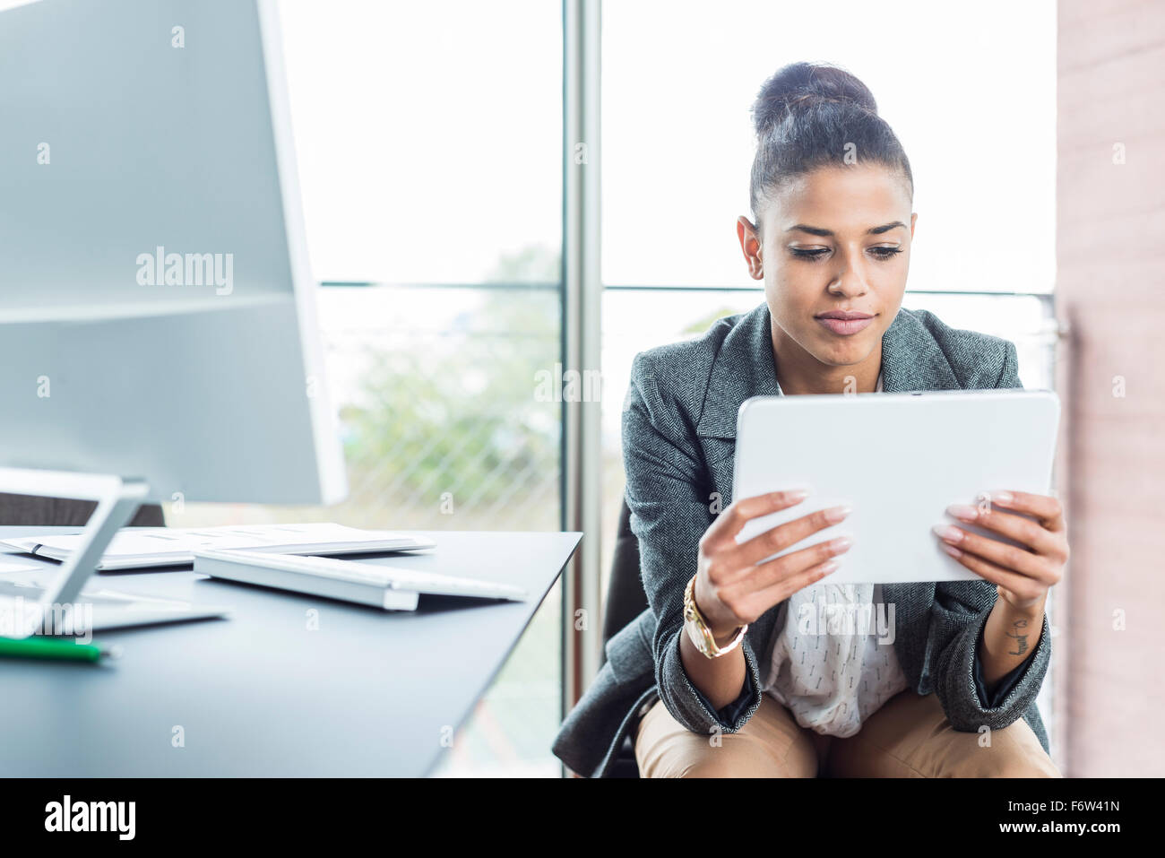 Young woman in office looking on digital tablet Stock Photo