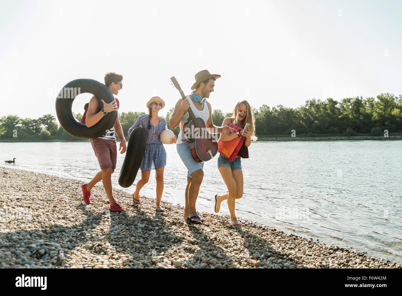 Friends With Inner Tubes And Guitar Walking At The Riverside Stock 