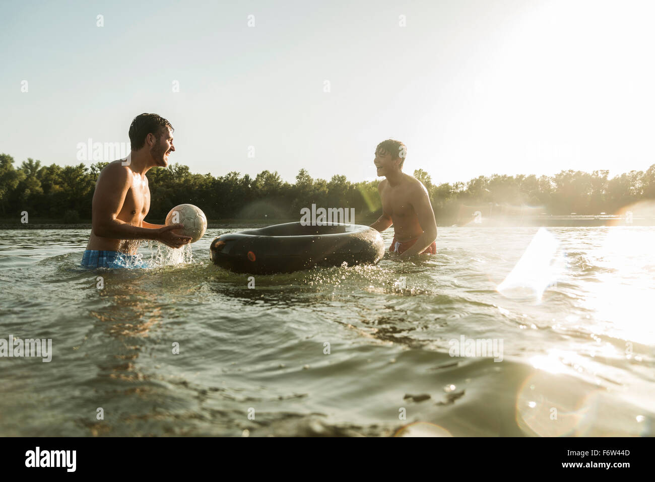 Two friends with inner tube and ball in water Stock Photo