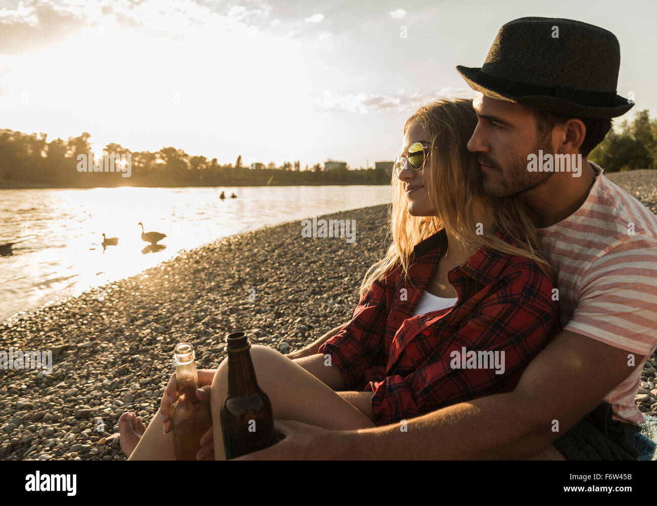 Young couple relaxing at the riverside at sunset Stock Photo