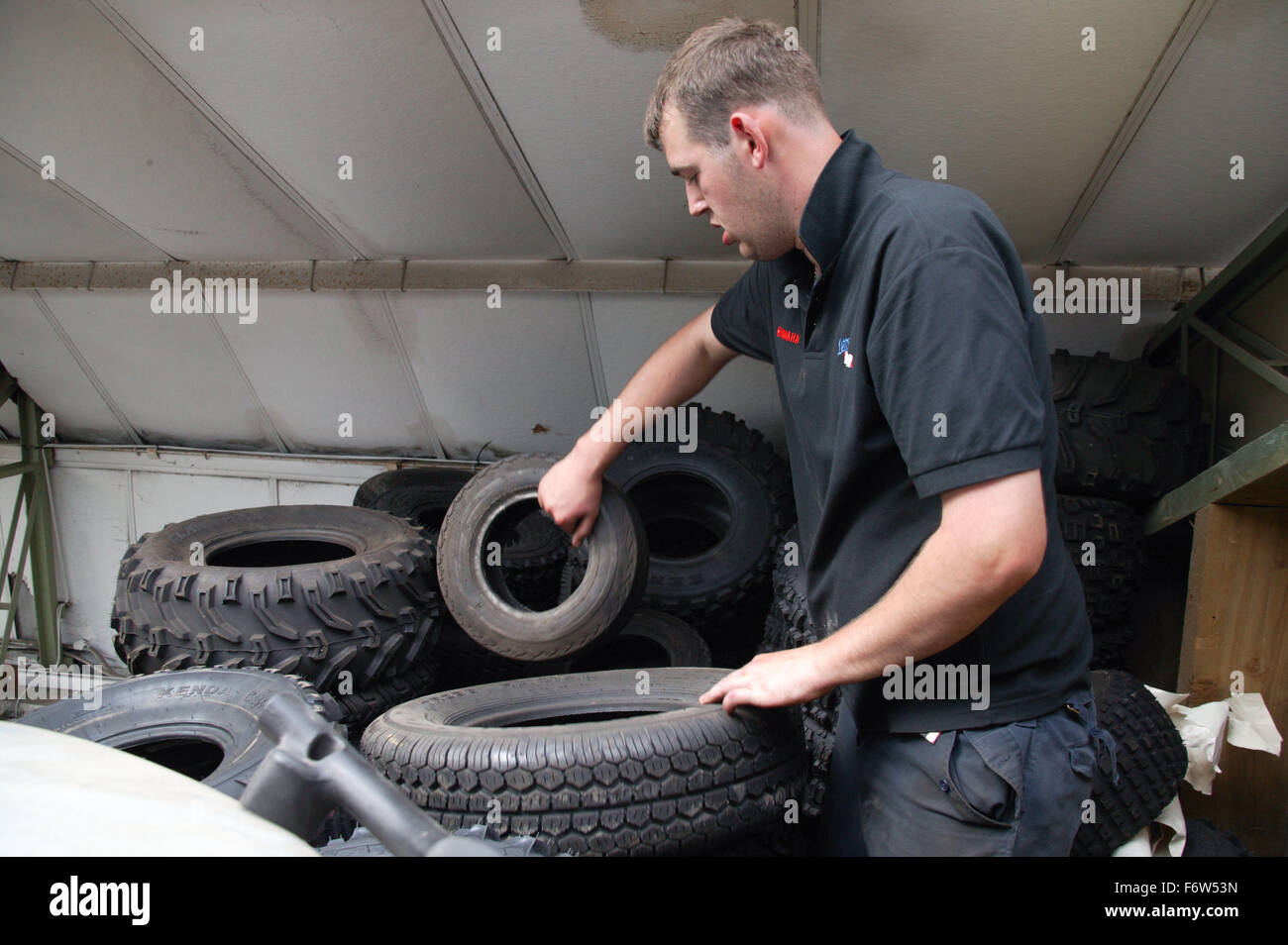 Man with Cerebral Palsy working as mechanic; sorting through tyres from ...