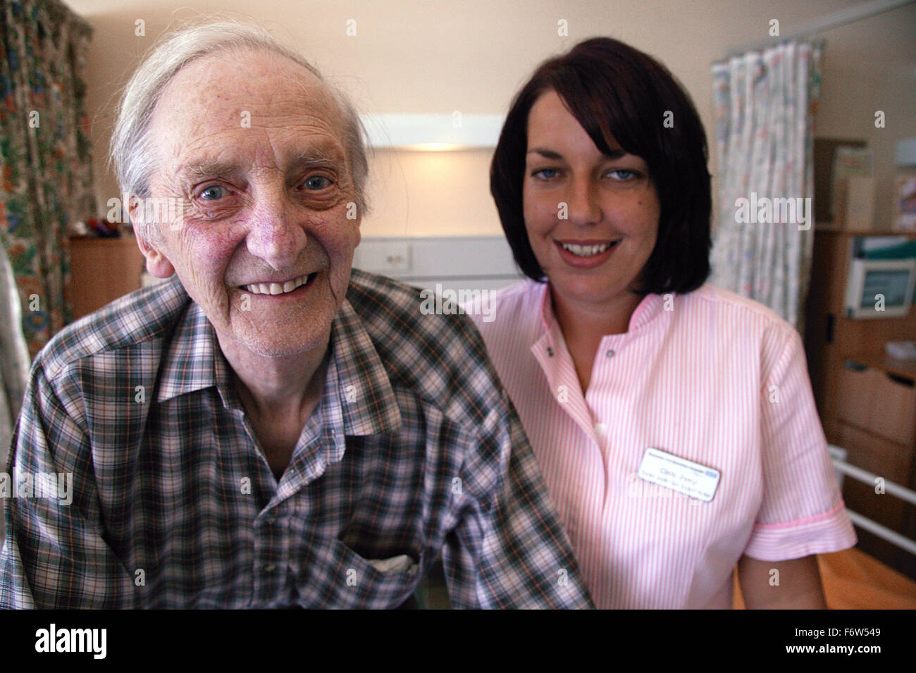 Health care worker and elderly patient standing together smiling, Stock Photo