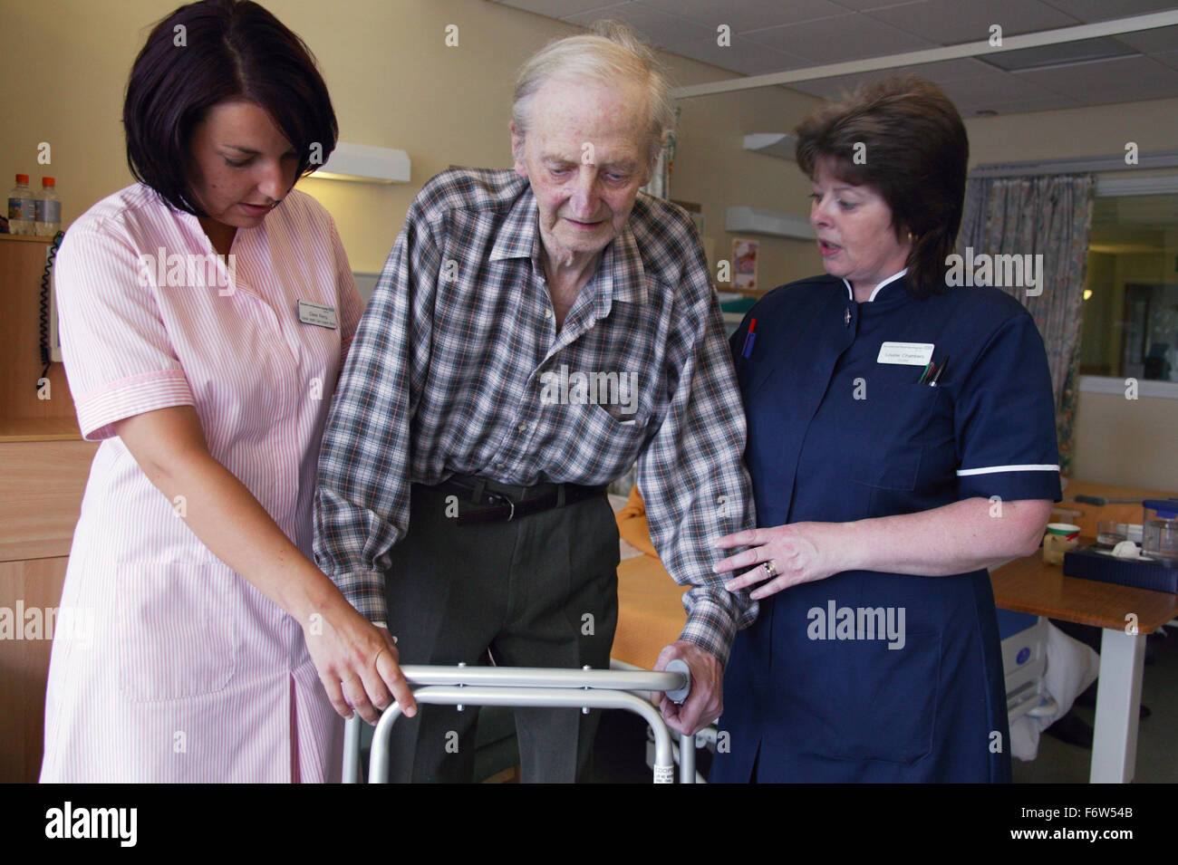 Nurse with disability and health care worker assisting elderly patient to mobilise using Zimmer frame, Stock Photo