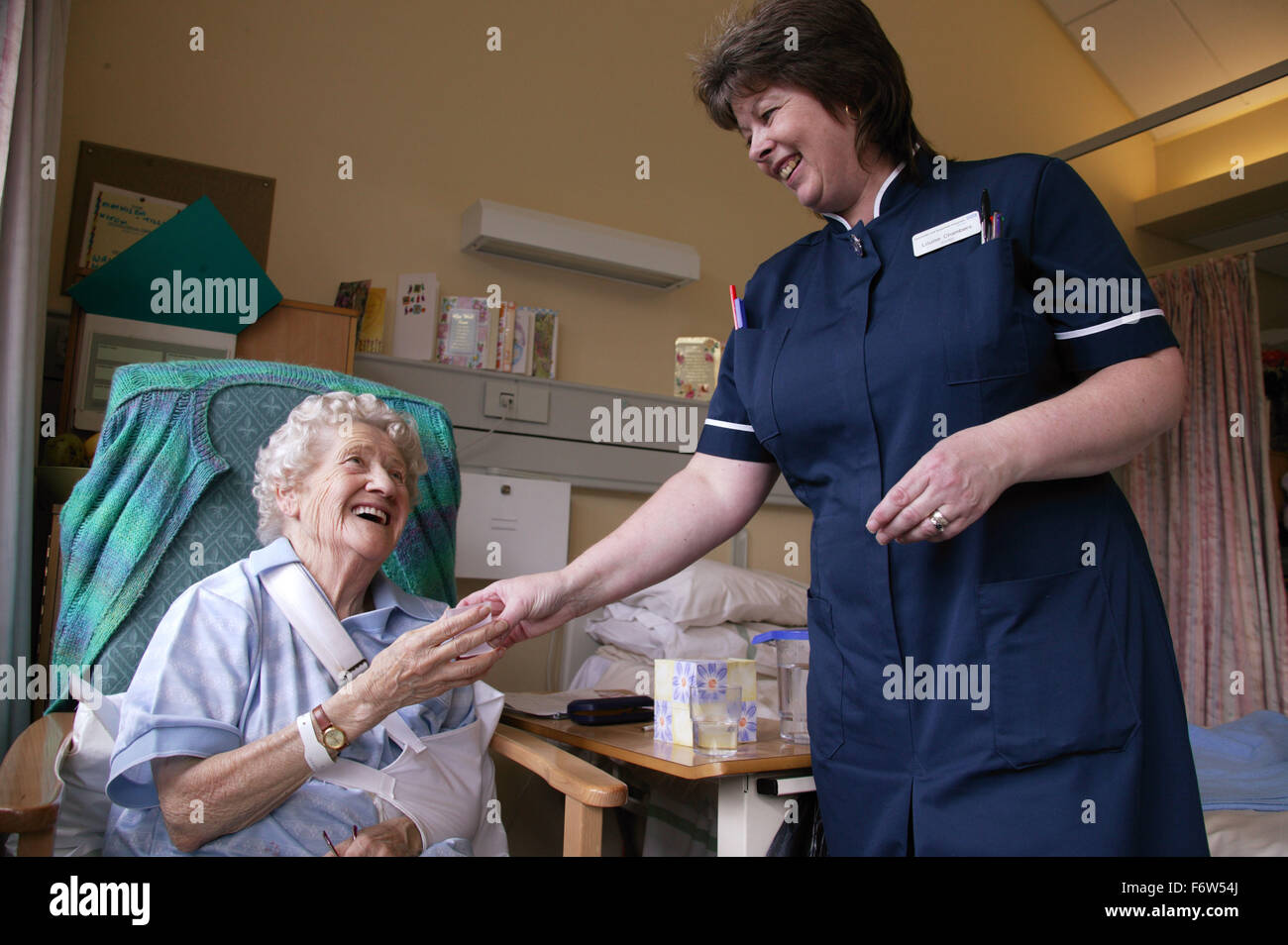 Nurse with disability administering medication to elderly patient in hospital, Stock Photo