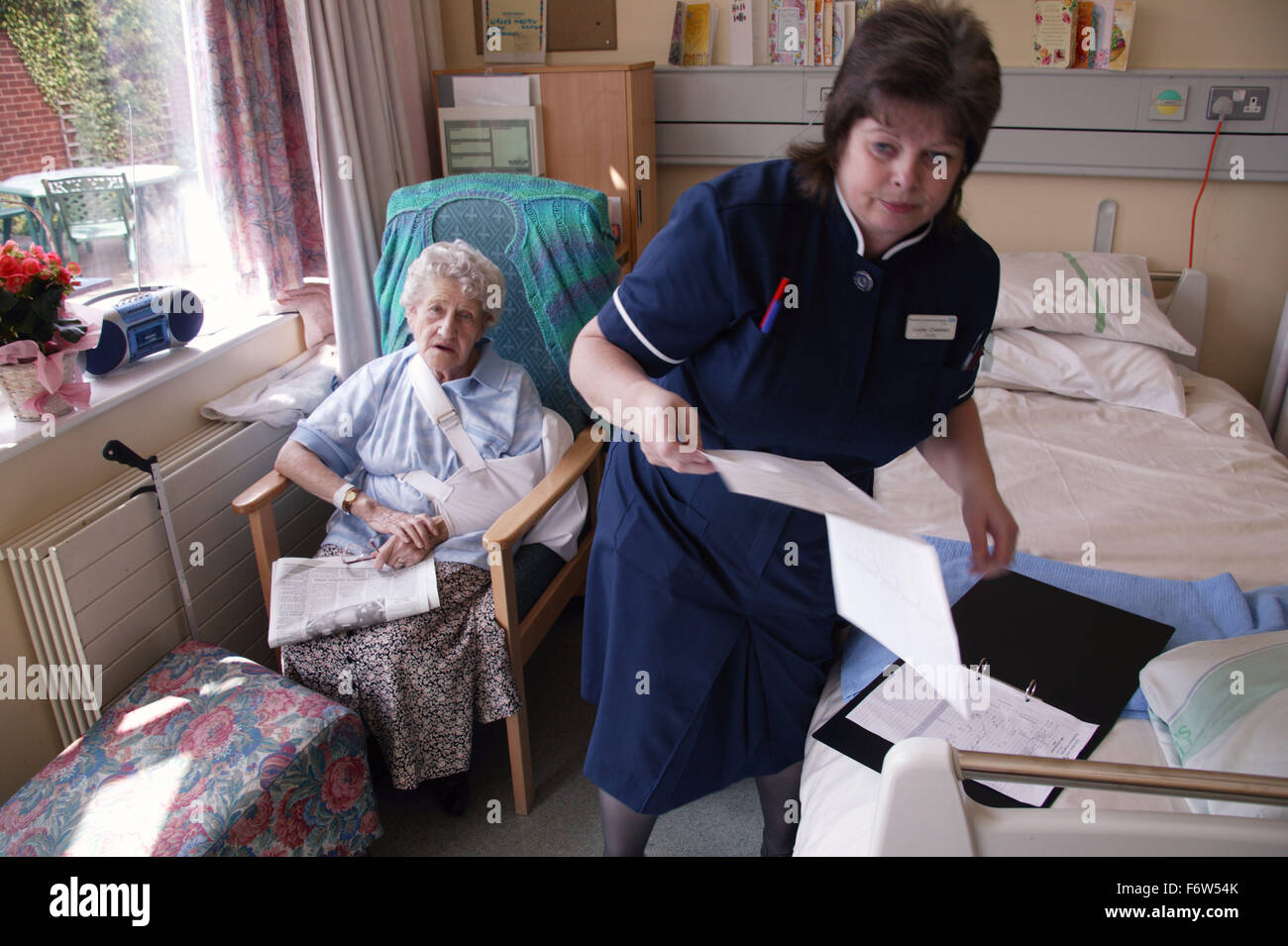 Nurse with disability consulting elderly patient's medical notes in hospital, Stock Photo