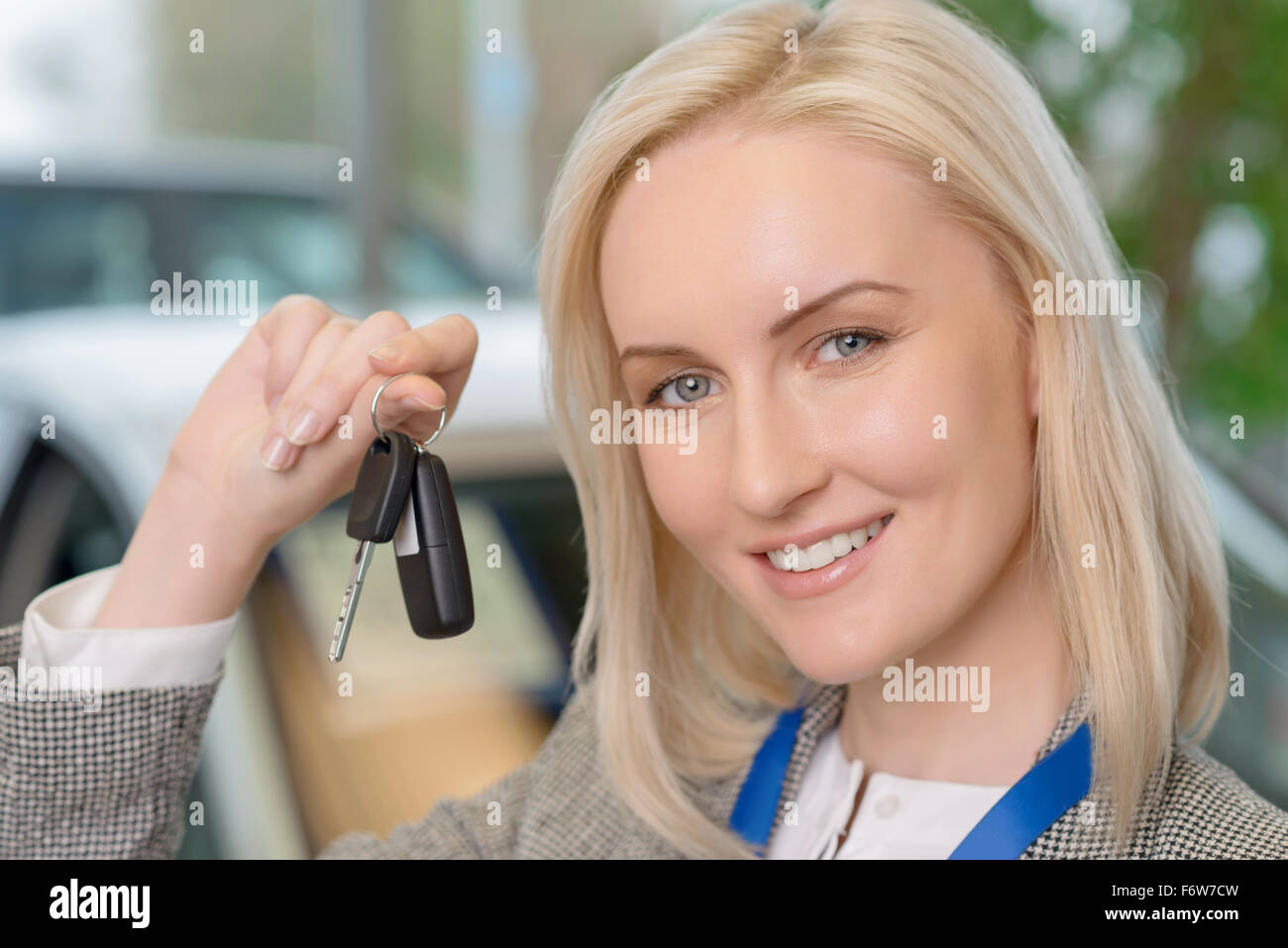 Smiling salesperson presenting a car key Stock Photo - Alamy