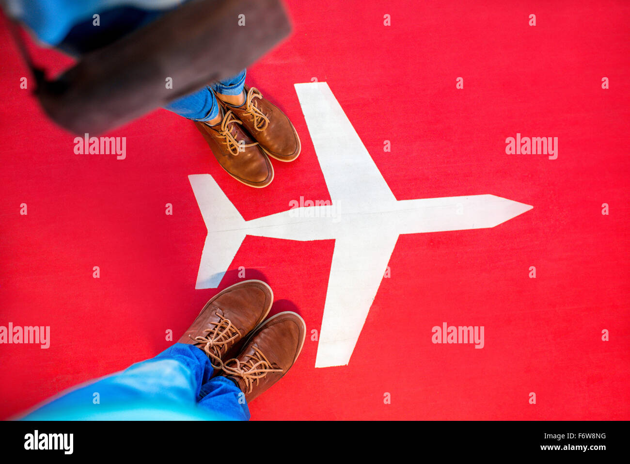 Airplane sign with couple's legs on the red background. Departure concept Stock Photo
