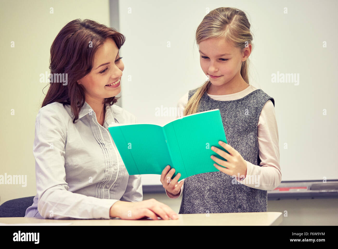 Instructor With Notebook school girl with notebook and teacher in classroom Stock Photo - Alamy