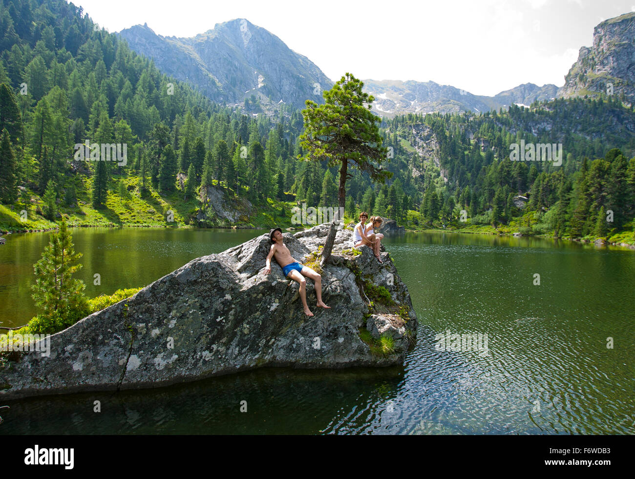 Young people sunbathing on a rock at lake Dieslingsee, Turracher Hoehe, Styria, Austria Stock Photo