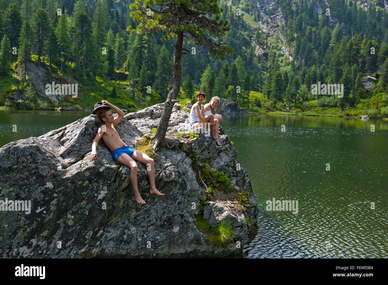 Young people sunbathing on a rock at lake Dieslingsee, Turracher Hoehe, Styria, Austria Stock Photo