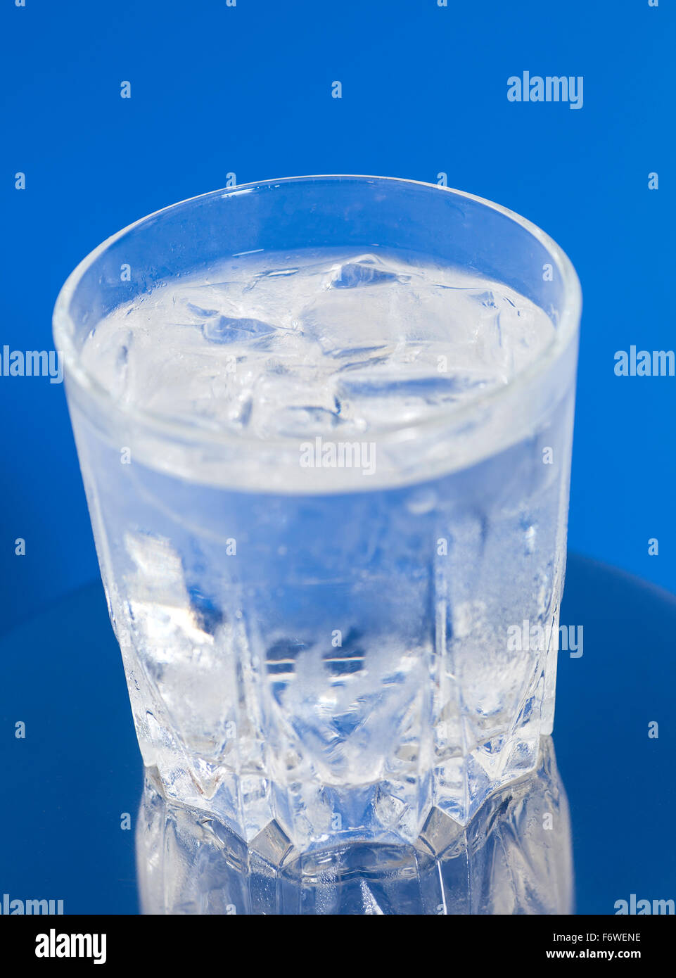 glass of water with ice on blue background Stock Photo - Alamy