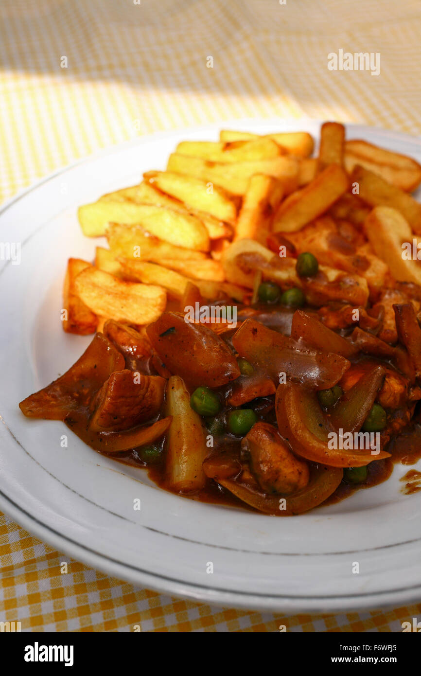 Chicken curry stir-fry and chips on a yellow checked tablecloth Stock Photo