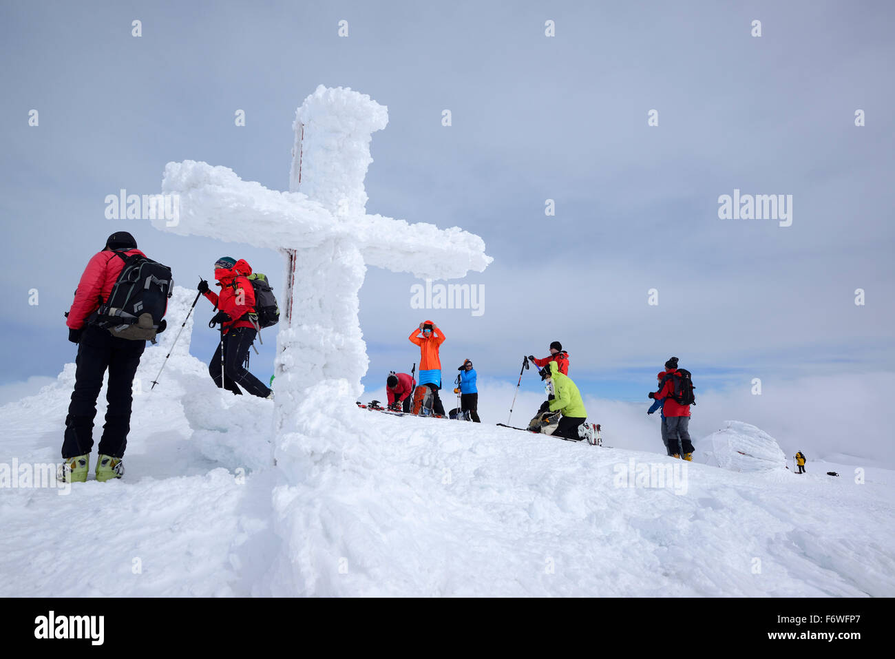 Group of persons back-country skiing standing on the summit of Monte Amaro with snow-covered cross, Monte Amaro, Majella, Abruzz Stock Photo