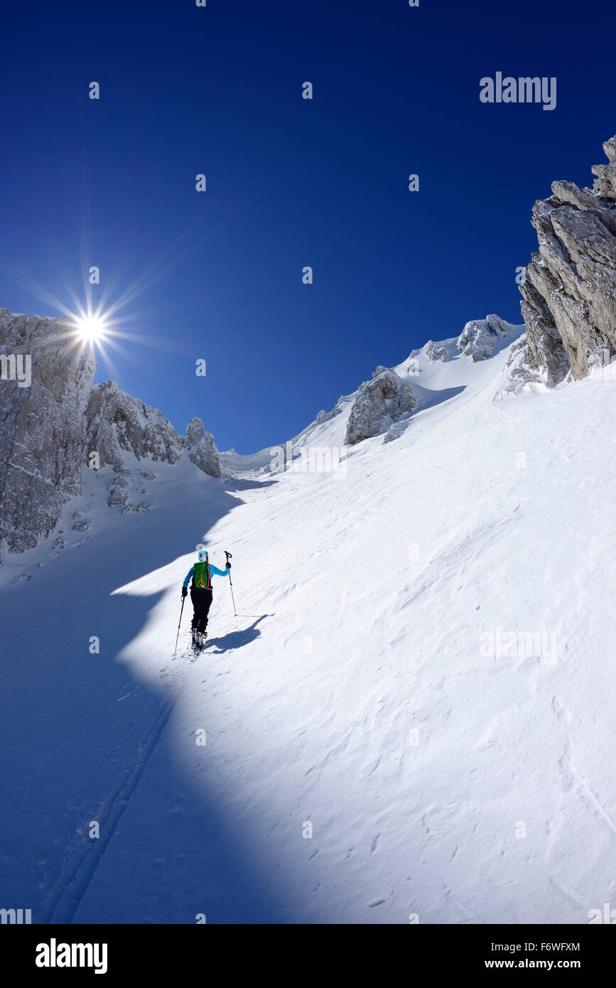 Female backcountry skier ascending through snow-covered cirque at Monte Sirente, Valle Lupara, Abruzzo, Italy Stock Photo