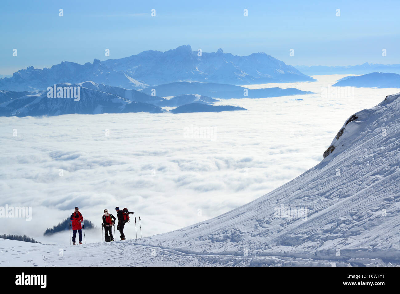 Three persons back-country skiing ascending to Hochkoenig, sea of fog in the valley of Salzach and Dachstein range in the backgr Stock Photo