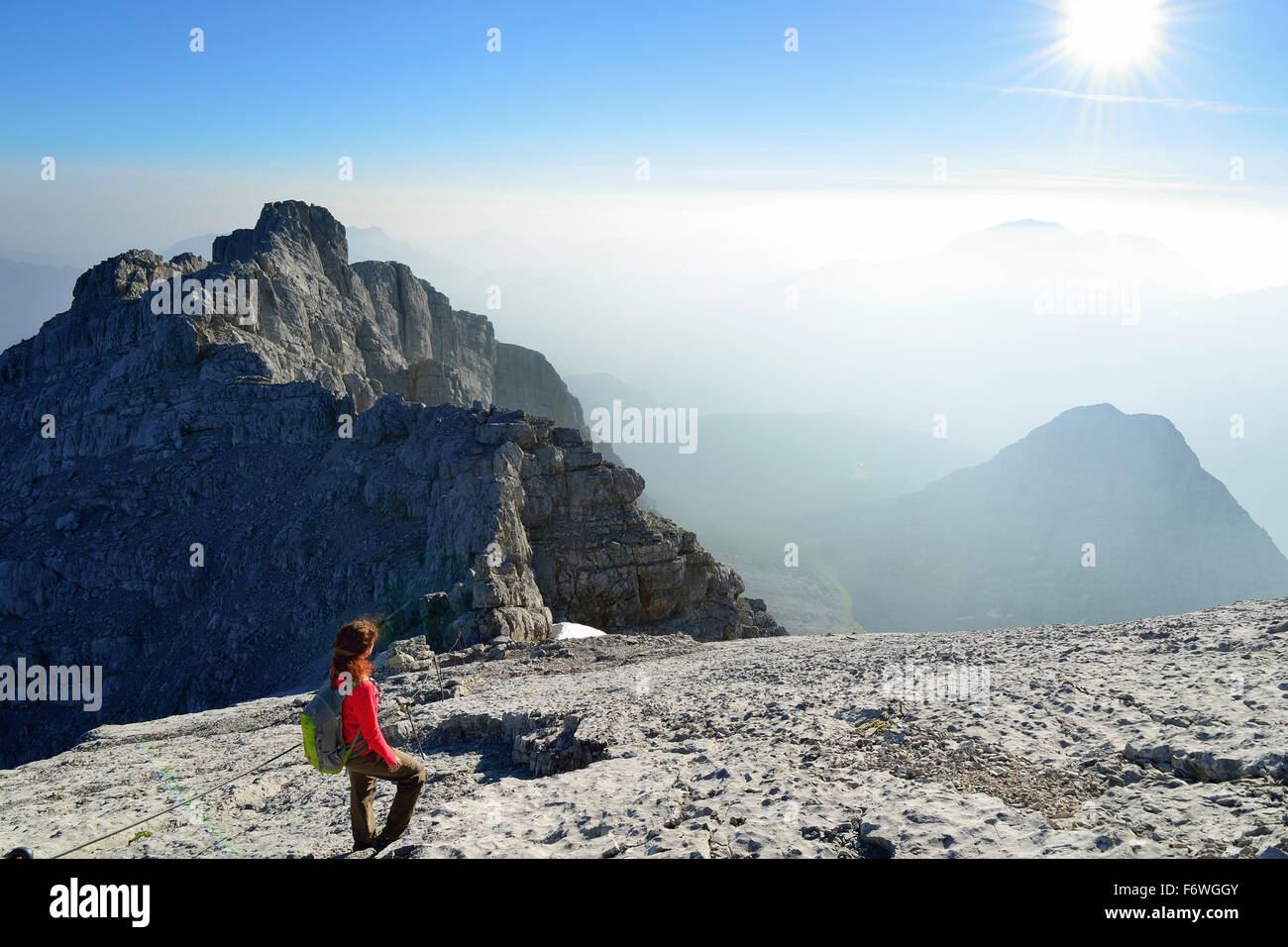 Woman standing on ledge and looking at view, Hocheck in background, Watzmann, Berchtesgaden Alps, Berchtesgaden National Park, B Stock Photo