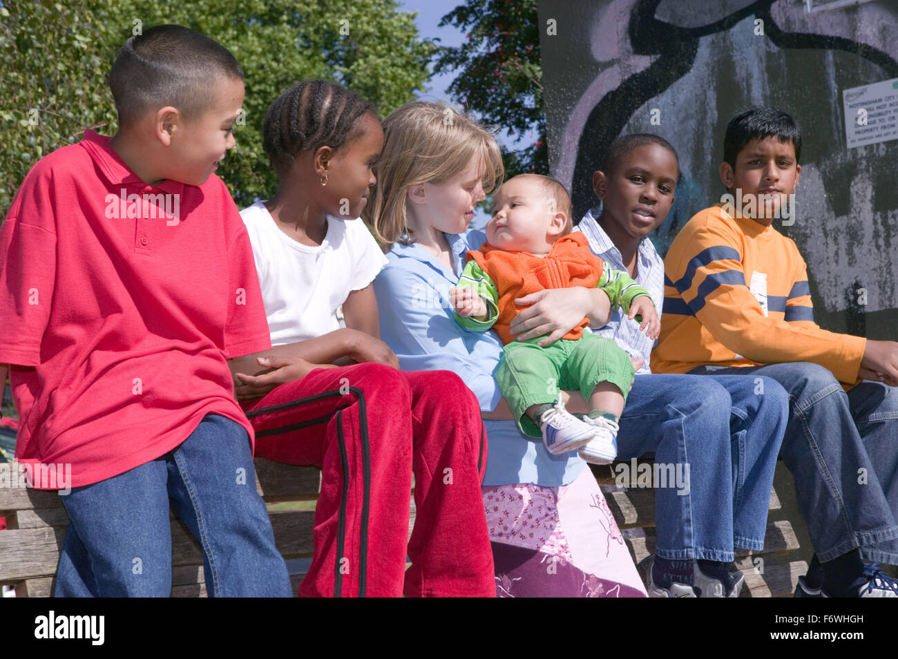 Group of young friends out in the park together; one of them holding a baby, Stock Photo