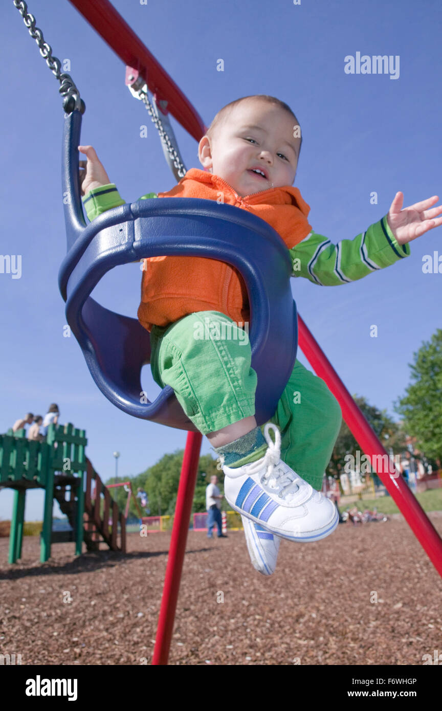Baby boy swinging in an infant's swing at the playground, Stock Photo