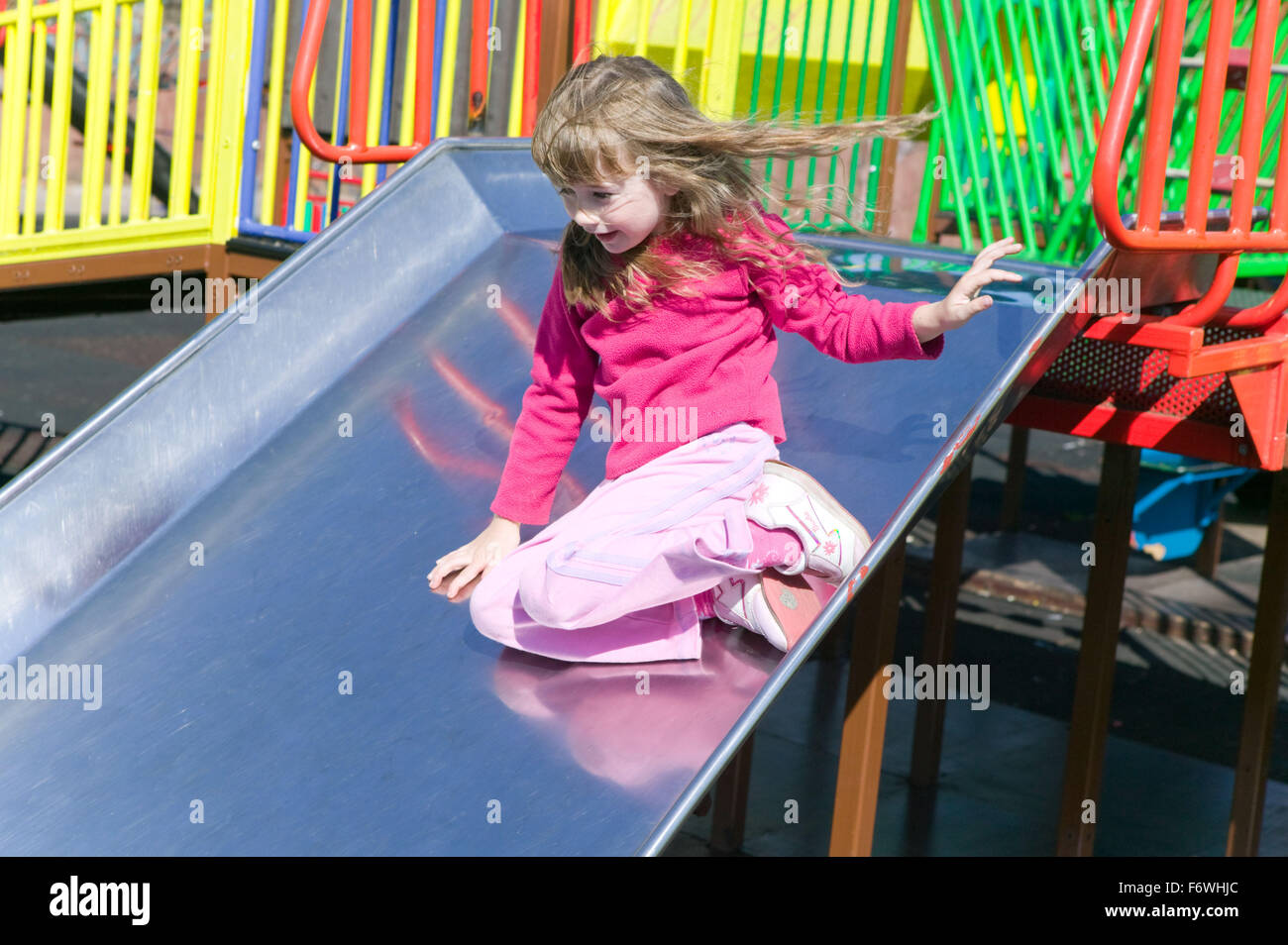 Little girl playing on a slide in the playground Stock Photo - Alamy