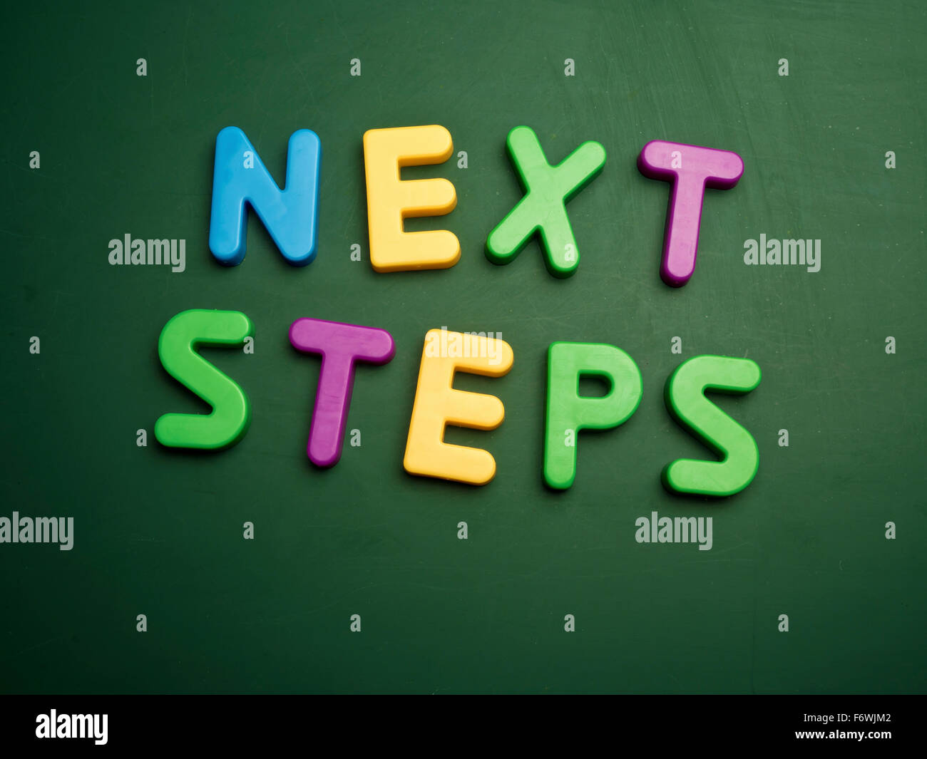 next steps concept in colorful letters isolated on blank blackboard Stock Photo