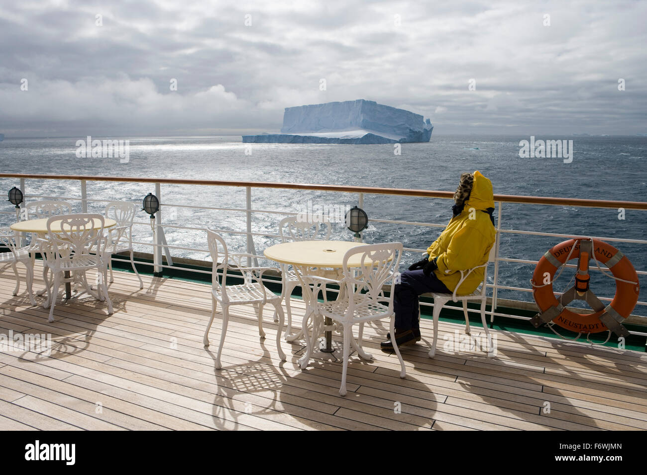 Woman relaxing on the deck of cruise ship MS Deutschland  Reederei Peter Deilmann  as vessel passes the Antarctic icebergs, near Stock Photo