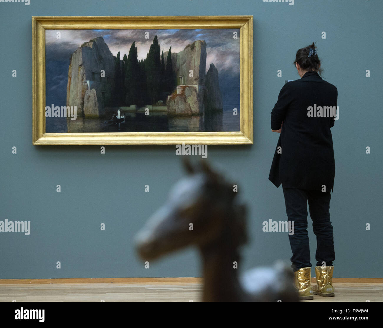 A woman looks at the painting 'Die Toteninsel' (lit. island of the dead') from 1883 by artist Arnold Boecklin during a preview of the exhibition 'The Black Years. Histories of a Collection: 1933?1945' at the Hamburger Bahnhof exhibition venue in Berlin, Germany, 20 November 2015. In the foreground stands the bronze sculpture titled 'Großes Vollblutfohlen' (lit. large thoroughbred foal) from 1940 by artist Renee Sintenis on display.   The exhibition showcases works of art  which were crafted during the Nazi era or confiscated by the Nazis. The exhibition 'The Black Years. Histories of a Collect Stock Photo