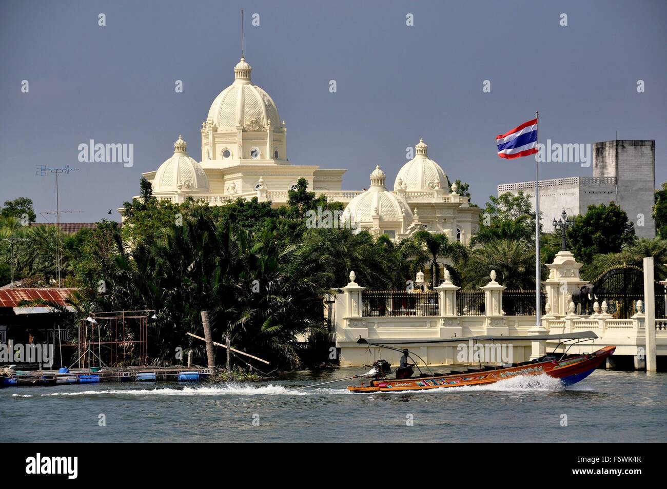 Samut Songkhram, Thailand:   A longtail boat flying the Thai flag passes a domed mansion built near the Mae Klong River Stock Photo