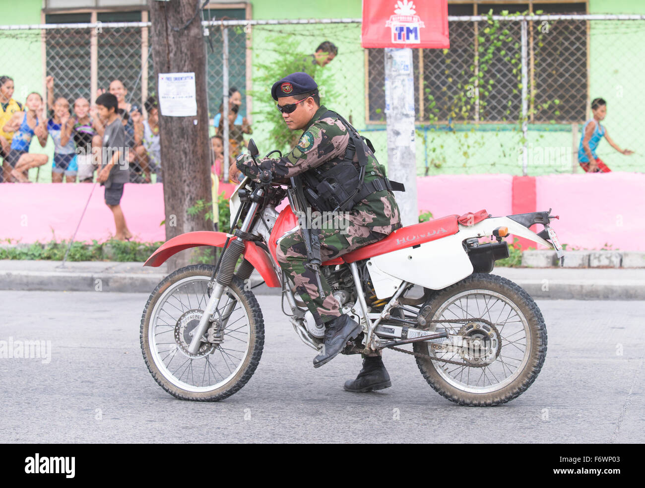 Heavily armed police man on a motorbike in front of Dadiangas South Central Elementary School in General Santos City. Stock Photo