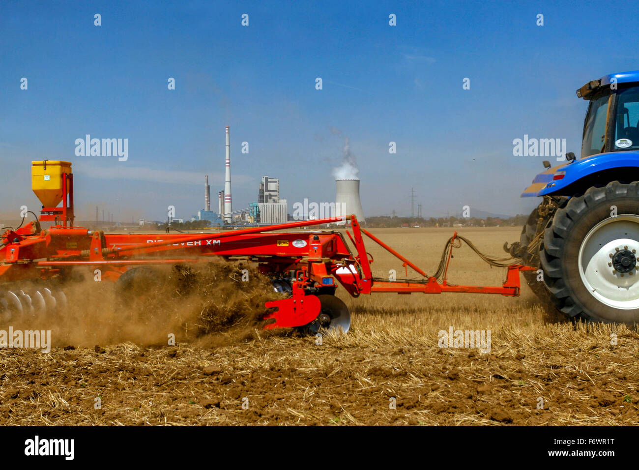 Tractor plowing field,season work, background thermal coal power plant Melnik Central Bohemia Czech Republic Stock Photo