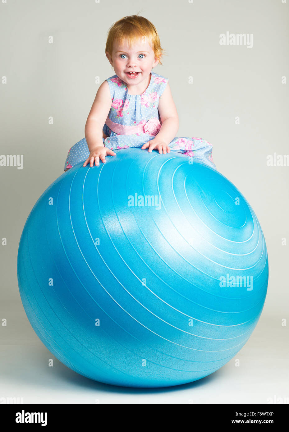 A cute little one year old girl sitting on a balance ball Stock Photo