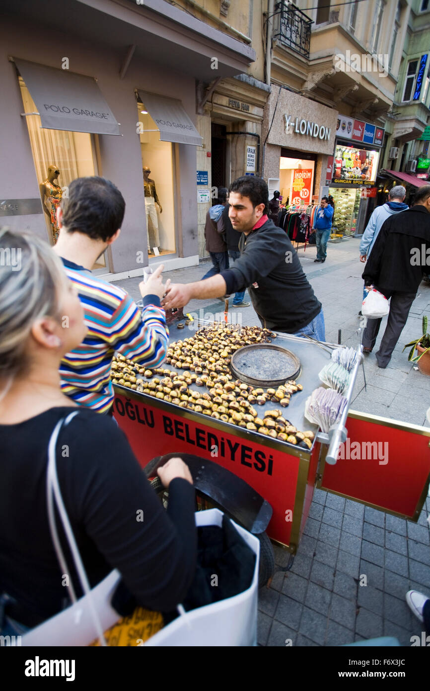 Hot roasted chestnuts are a popular snack along Istanbul's busy pedestrian shopping street Istiklal Caddesi, Beyoglu District. Stock Photo