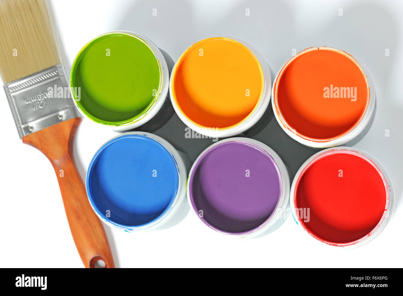 Cans of different colors and paintbrush over light background Stock Photo