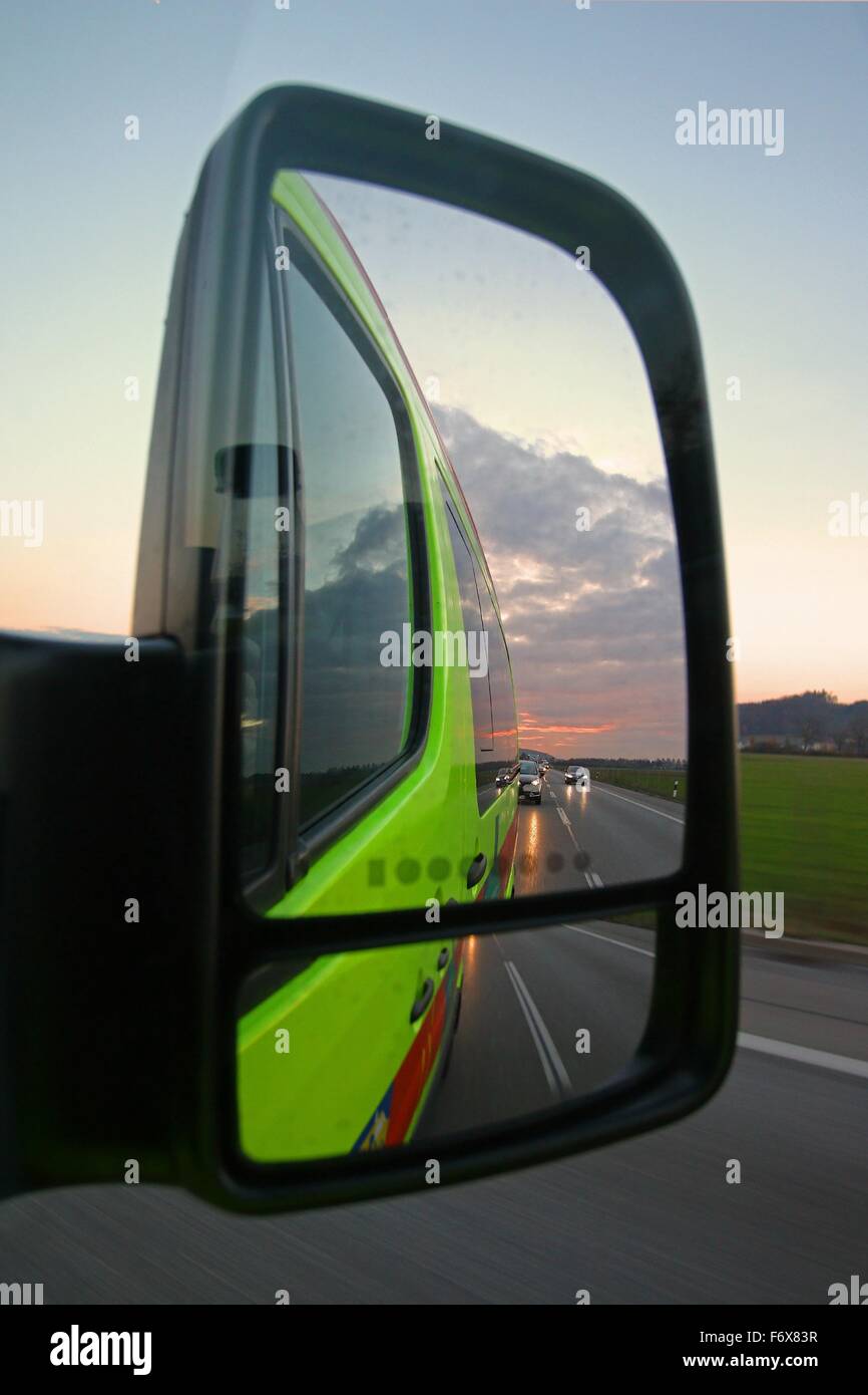 Highway traffic with headlights and sunset in a rear view mirror of an emergency vehicle Stock Photo