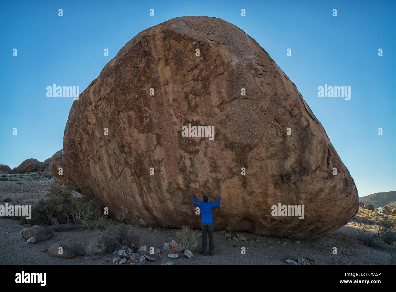 Person standing under a large boulder in Richtersveld National Park; South Africa Stock Photo