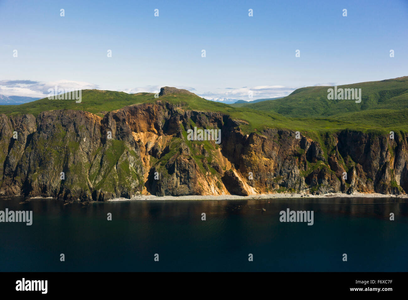 Aerial view of rocky cliffs and green hills along the shore of Popof