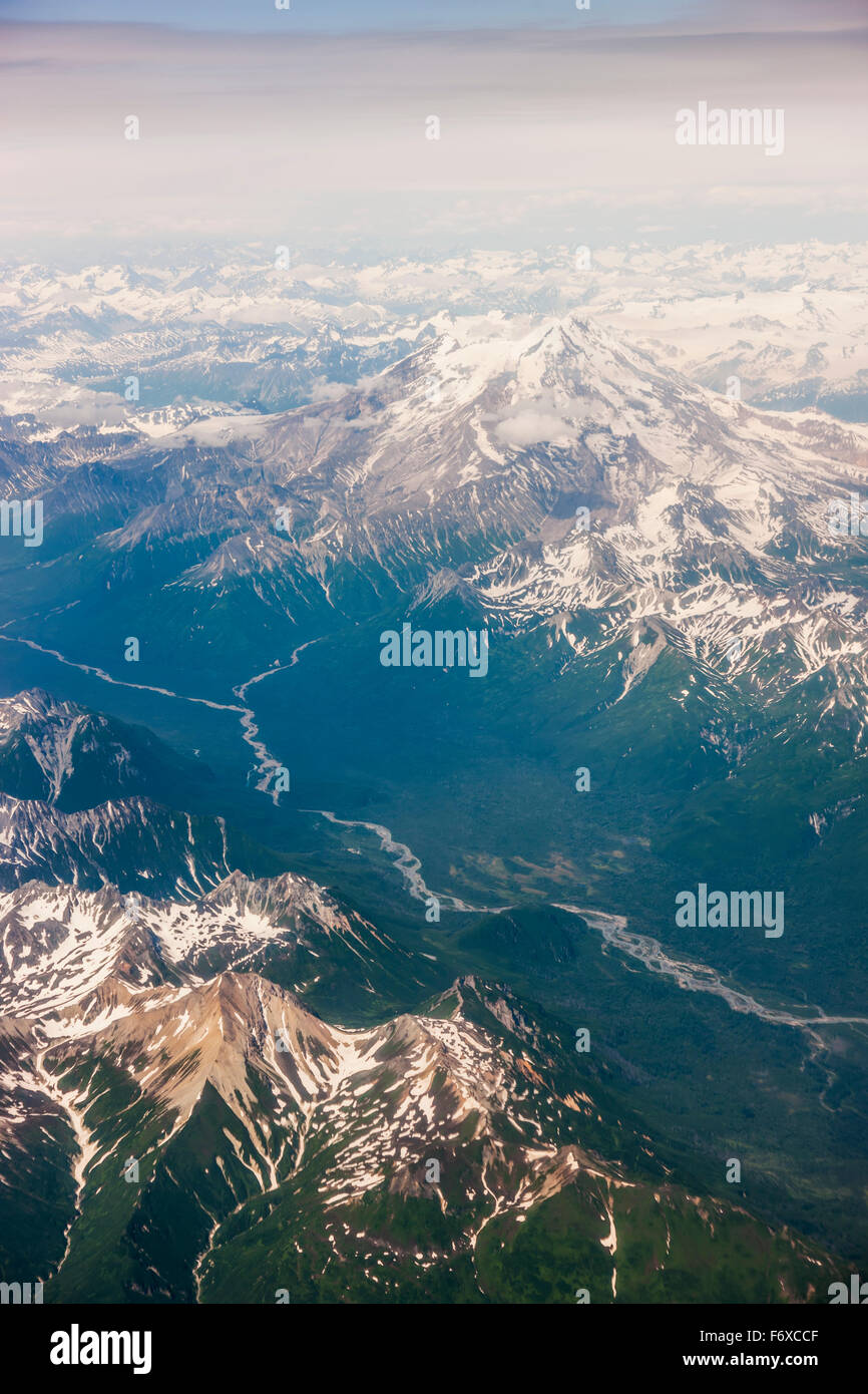 Aerial view of snowcapped peaks surrounding a green river valley