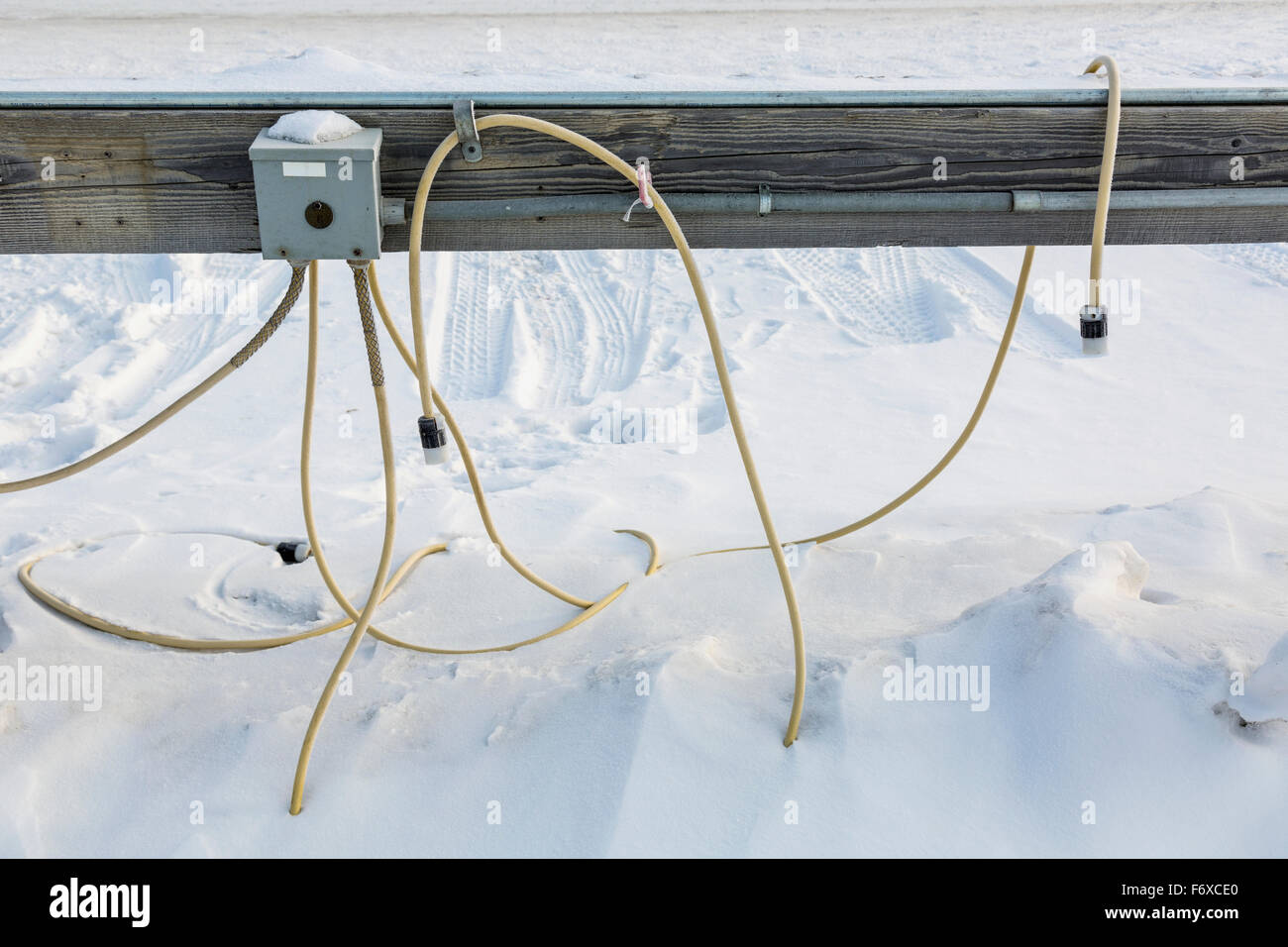 Detail view of extension cords buried in snow running from an outdoor power outlet, Barrow