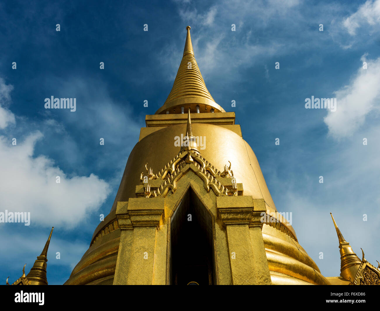 Gold structure with spire against a blue sky and cloud, Temple of the Emerald Buddha (Wat Phra Kaew); Bangkok, Thailand Stock Photo