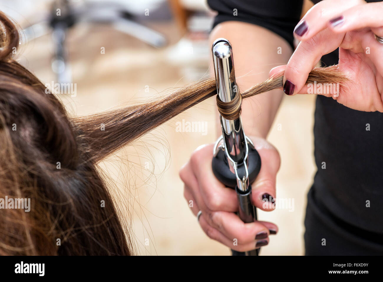 Hairstylist using a curling iron to firm ringlets, closeup view of the hand Stock Photo