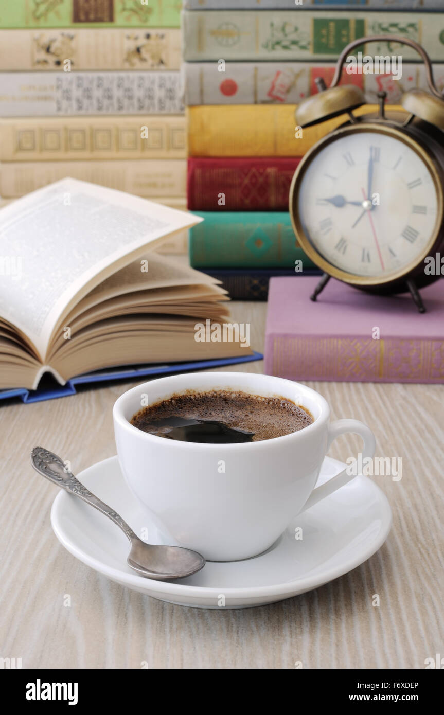 A cup of coffee on the table against the background of an open book ...