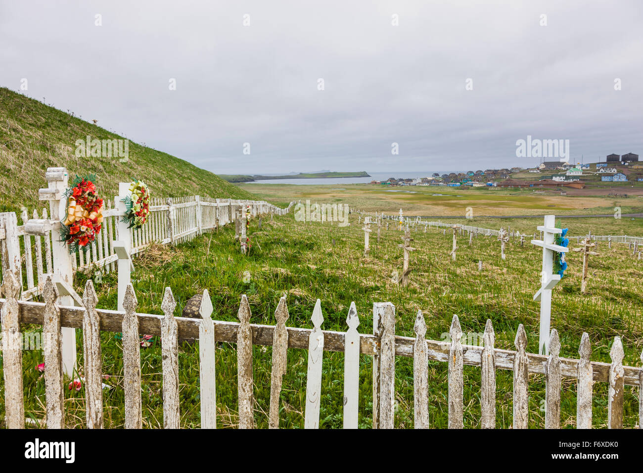 A weathered picket fence surrounds the grave crosses in the cemetary