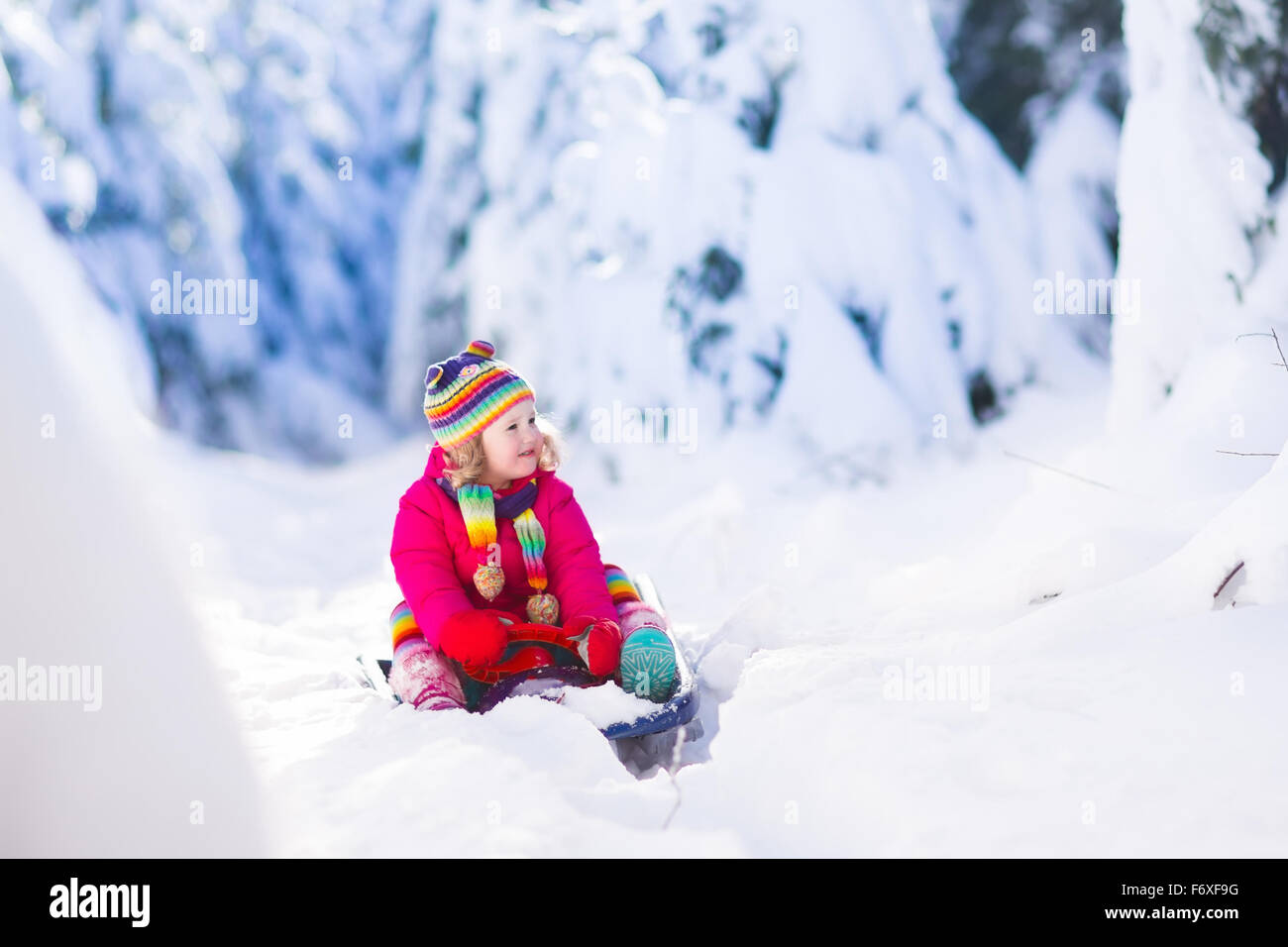 Funny little toddler girl playing snow ball fight. Kids play outdoors in winter. Children having fun at Christmas time. Stock Photo