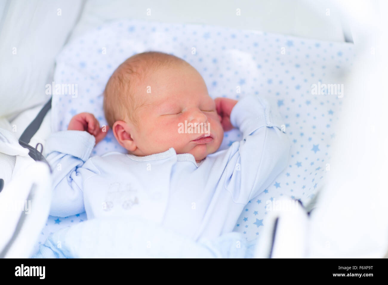 Newborn baby boy in bed. New born child sleeping under a blue knitted