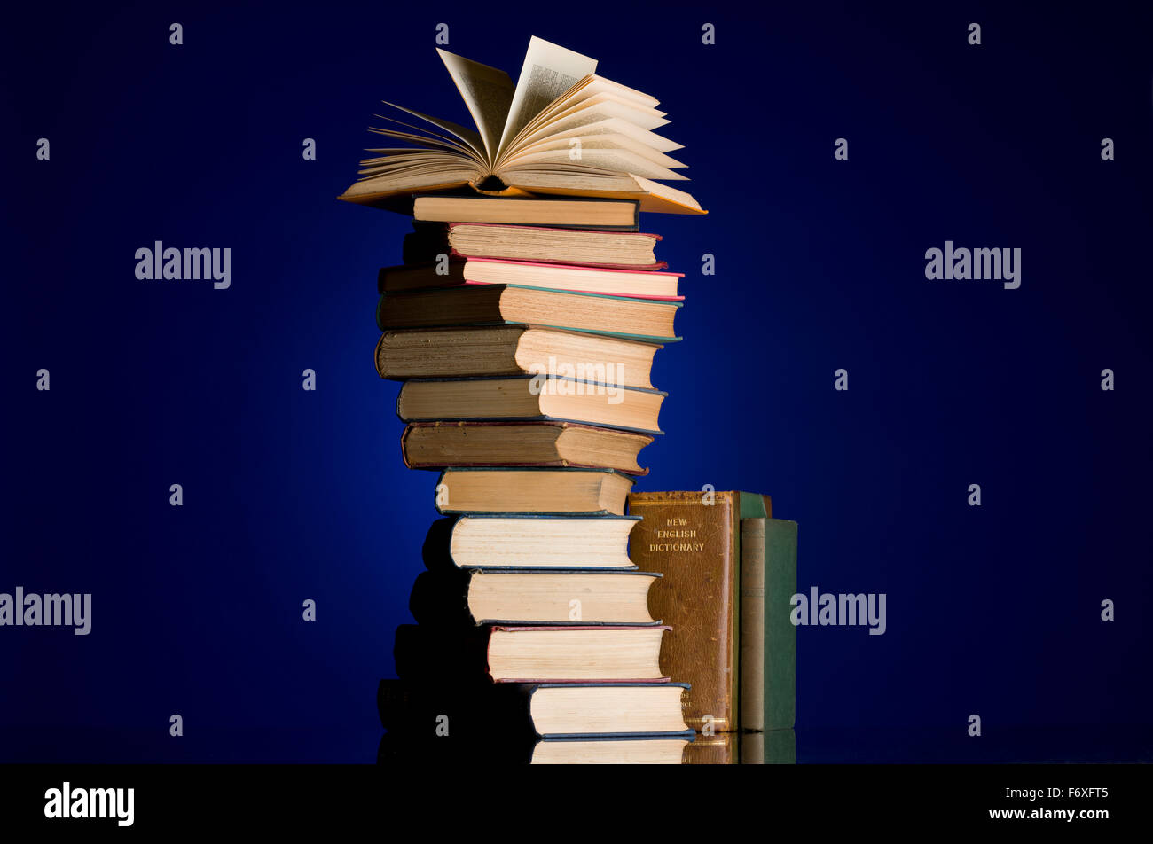 Pile of old books in a spiral twist. Open book at the top of the pile. Book collection. Read, education metaphor. Stock Photo