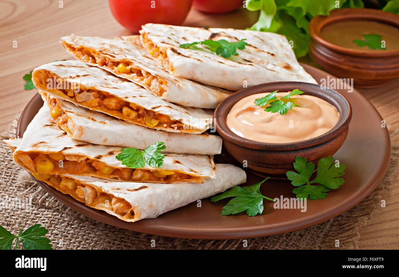 Mexican Quesadilla sliced with vegetables and sauces on the table Stock Photo